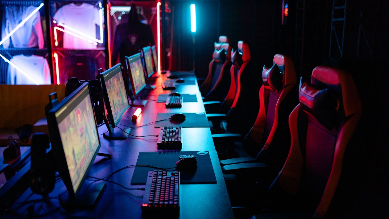 Row of esports PC stations with neon lighting and gaming chairs